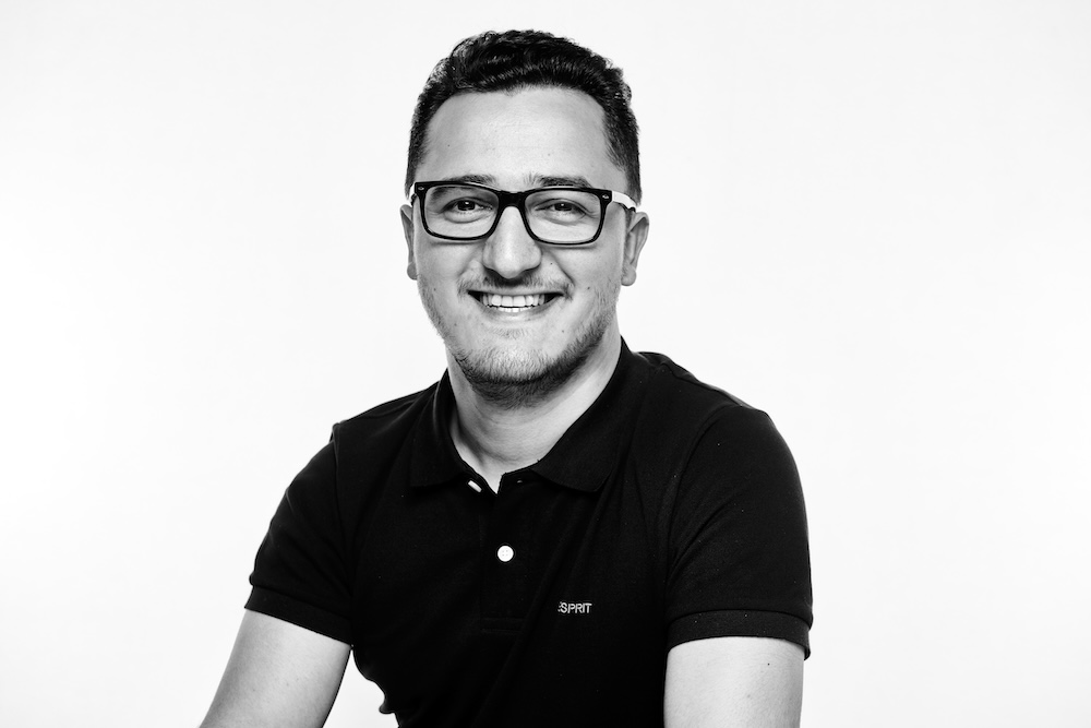 Ayaz Guliyev is smiling, wearing a black polo shirt and glasses